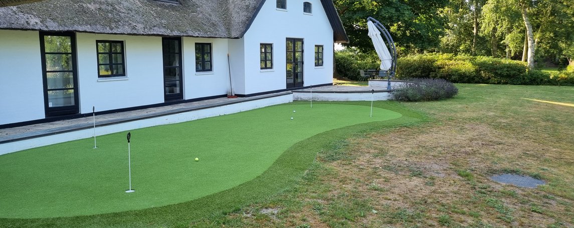 Golfdesign Clock green med stenkant og kunstgræs i haven